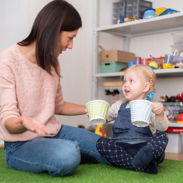 Woman speech therapist helps little girl to correct her speech in her office